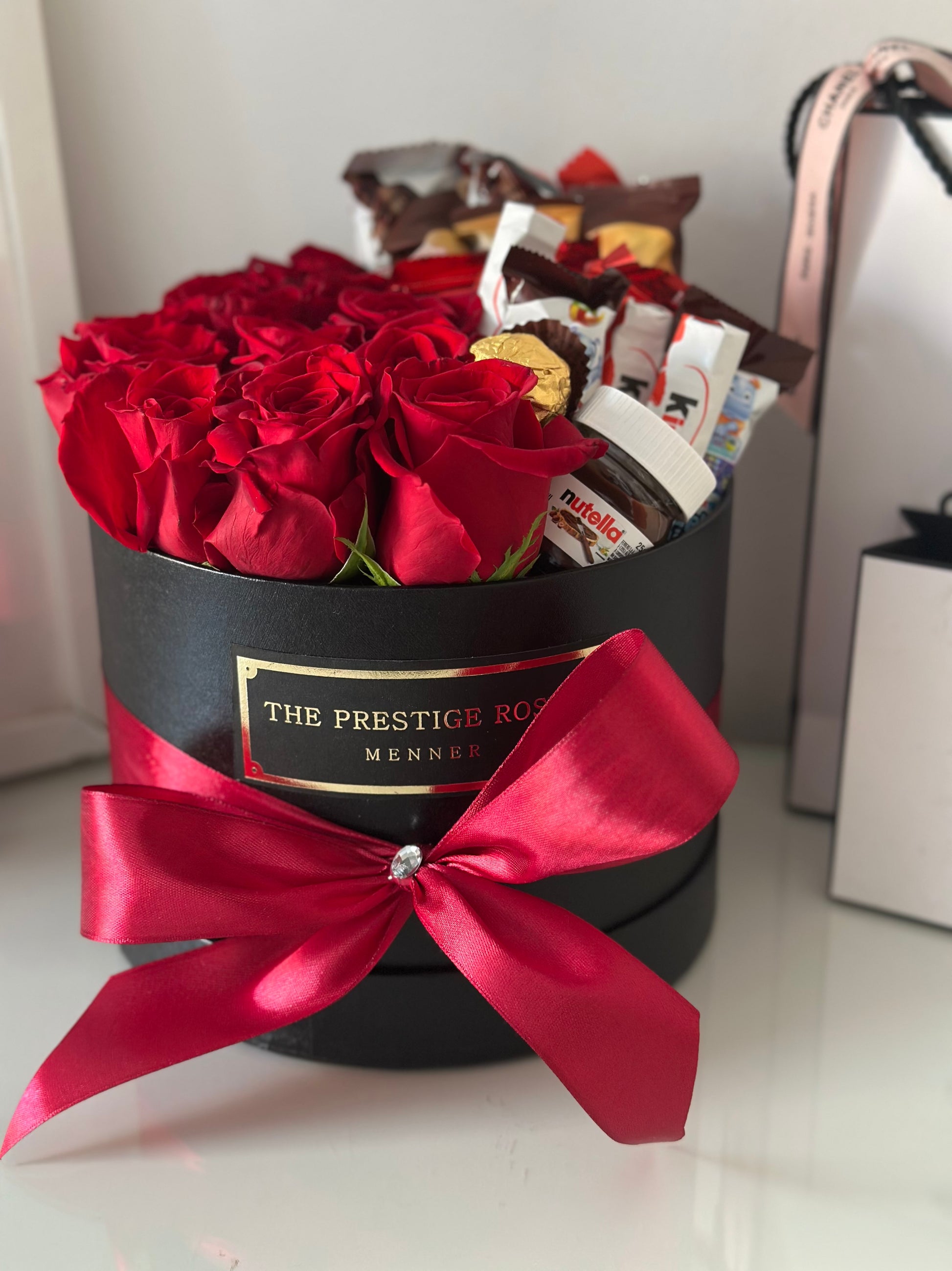 Sorpresa elegante: rosas rojas frescas con surtido de chocolates en caja negra The Prestige Roses.