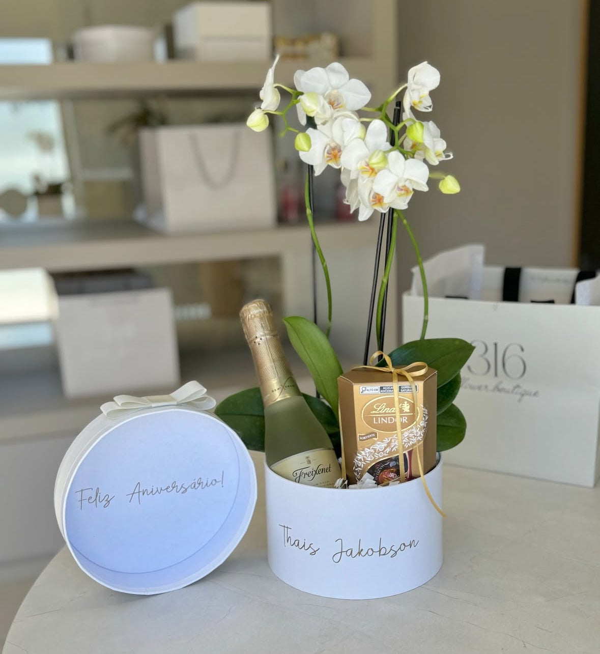 Caja regalo personalizada con nombre y con orquídea, champagne  y chocolates Lindt Lindor.