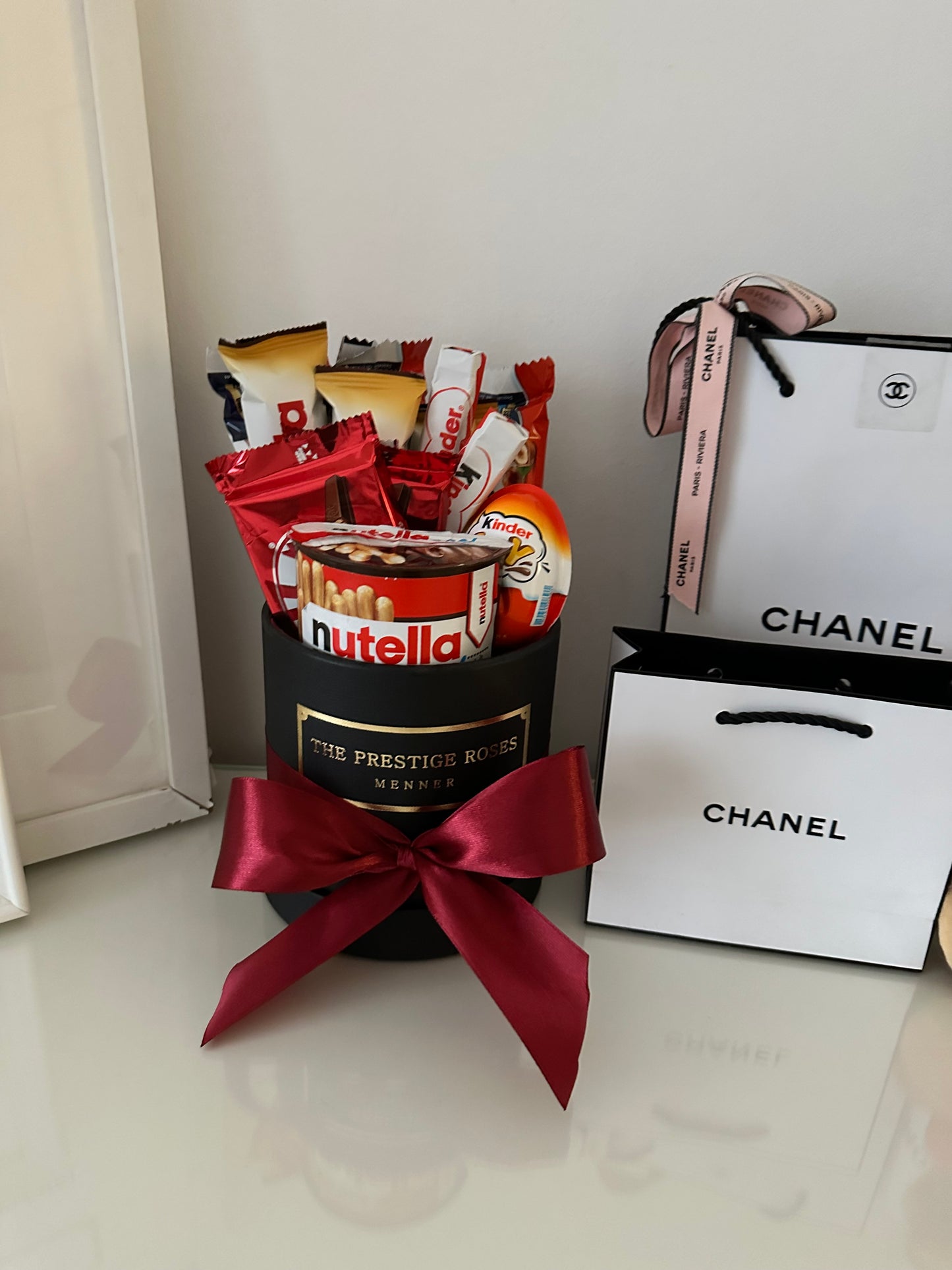 The Prestige Roses: caja negra con lazo rojo, rosas rojas y chocolates Kinder Ferrero.