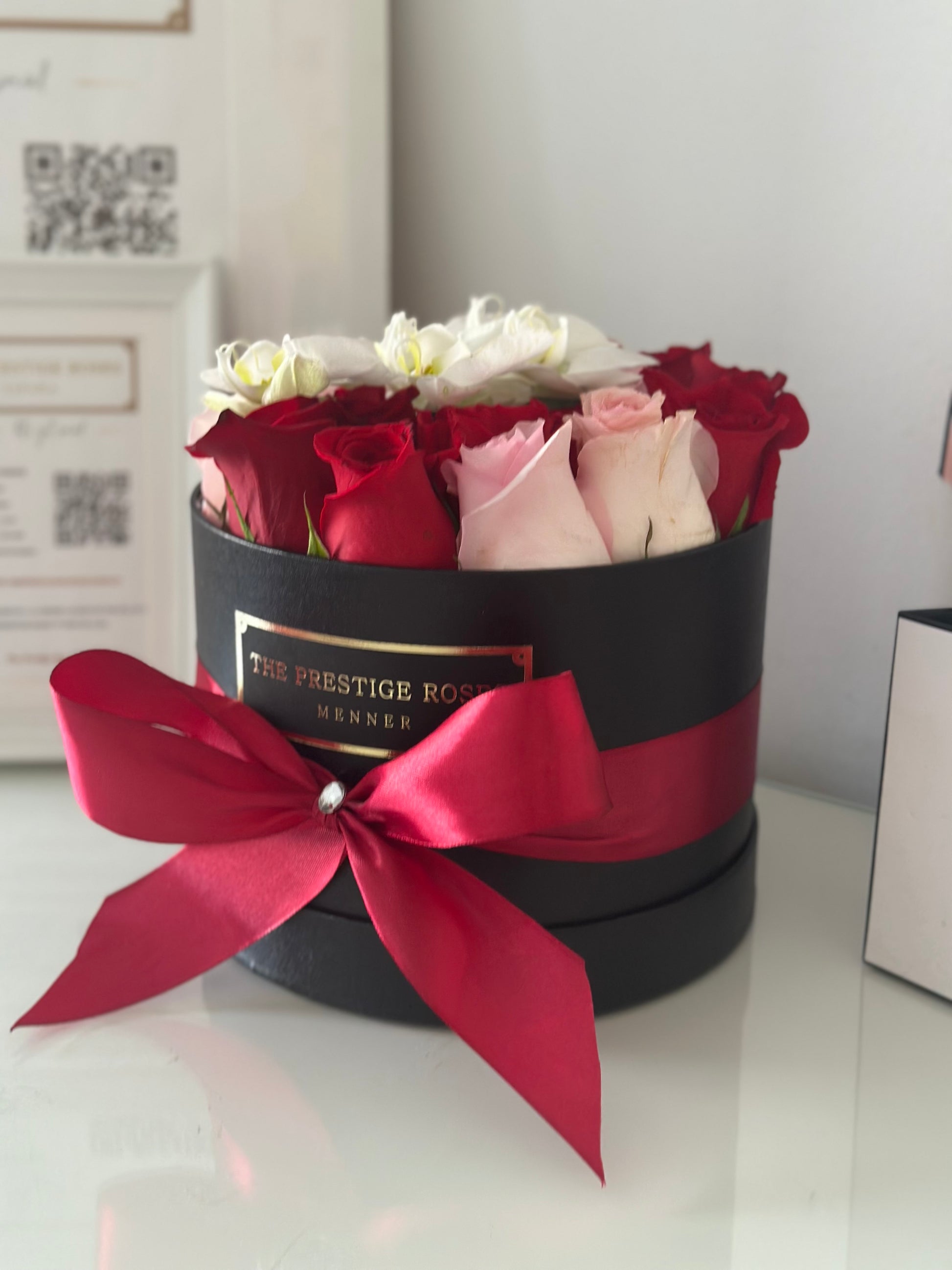Arreglo floral en caja mediana de lujo, combinando rosas frescas y orquídeas blancas, ideal para regalo romántico.