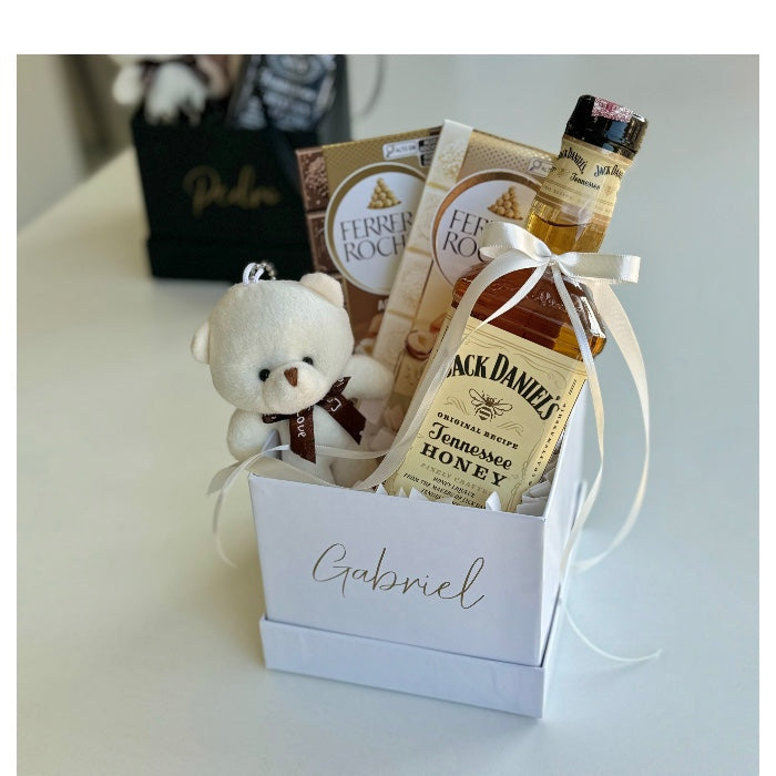 Caja blanca con osito, Jack Daniel’s y Ferrero Rocher, decorada con lazo blanco y nombre personalizado a domicilio en Madrid