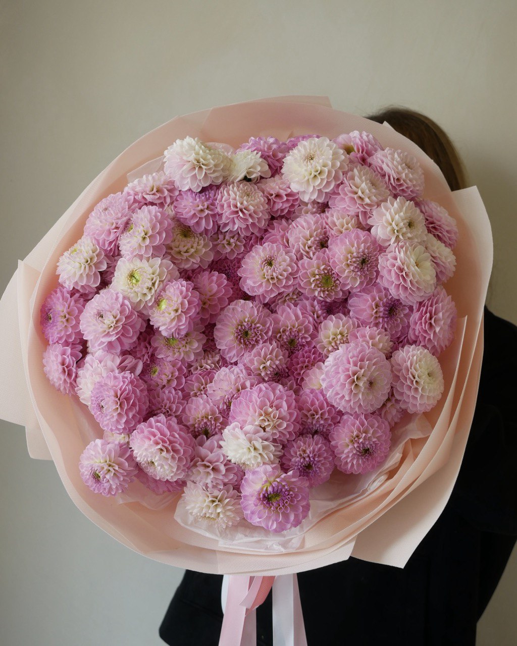 Ramo de dalias rosas naturales envuelto en papel premium con cinta satinada de lujo.