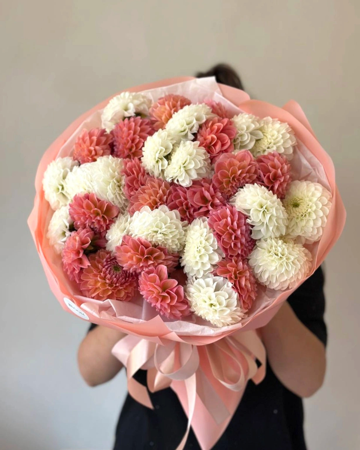 Bouquet de dalias frescas de temporada con papel blanco y cinta rosa, diseño artesanal de The Prestige Roses Madrid