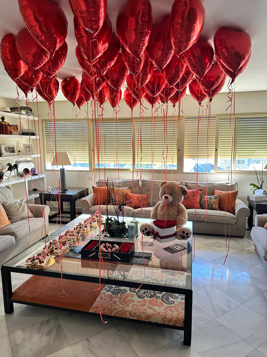 Decoración de globos rojos con osito y mesa de dulces para baby shower