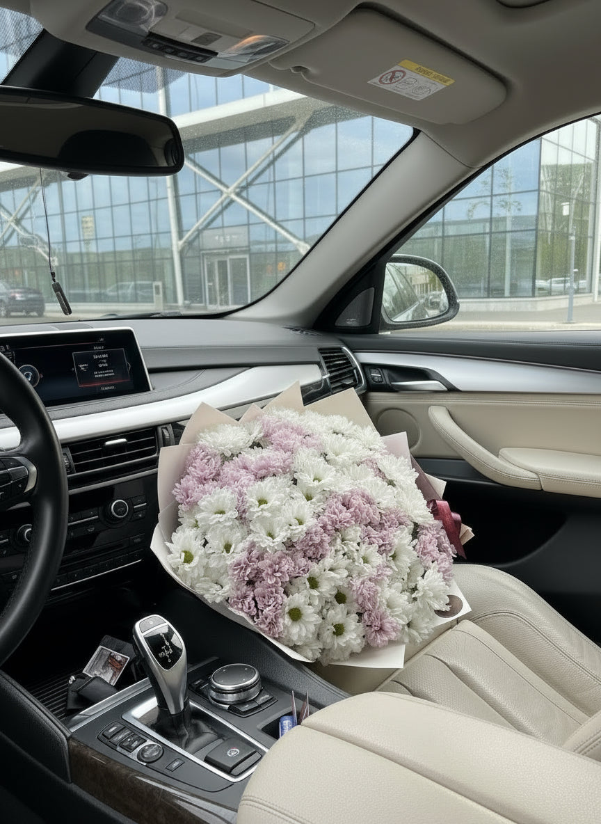 Ramo de margaritas blancas y rosas envuelto en papel de lujo sobre el asiento de un coche – The Prestige Roses Madrid