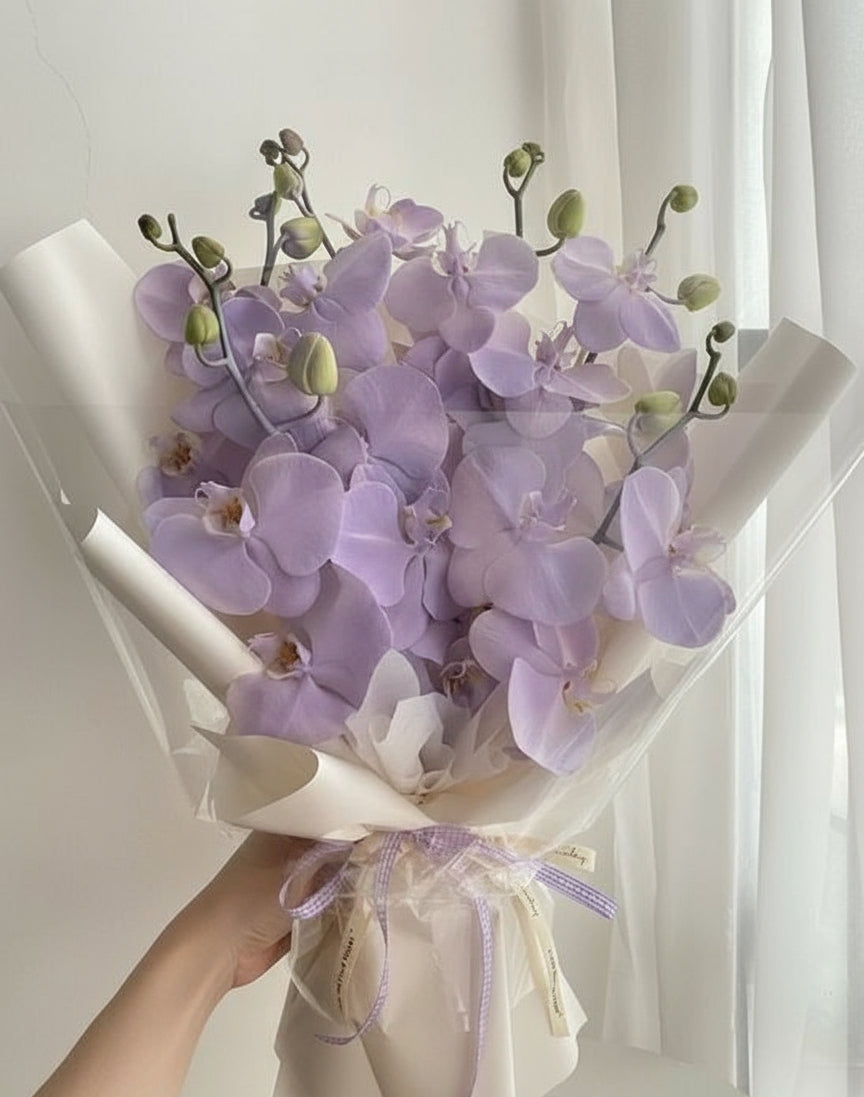Ramo de orquídeas lilas envuelto en papel blanco satinado con lazo elegante, flores frescas y delicadas – The Prestige Roses Madrid
