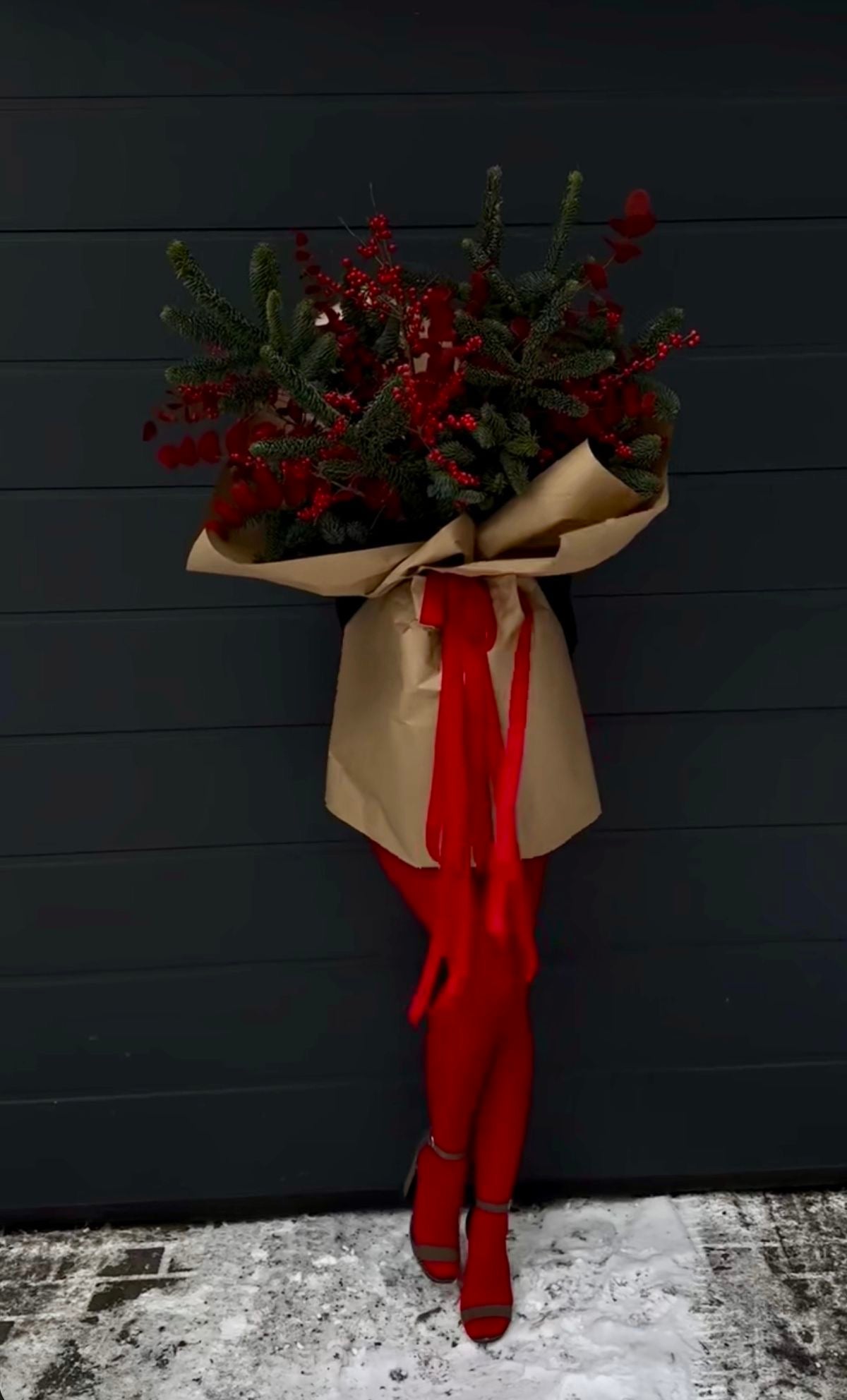 Bouquet de Navidad elegante con ramas de abeto, conos de pino y cinta roja satinada de The Prestige Roses Madrid.