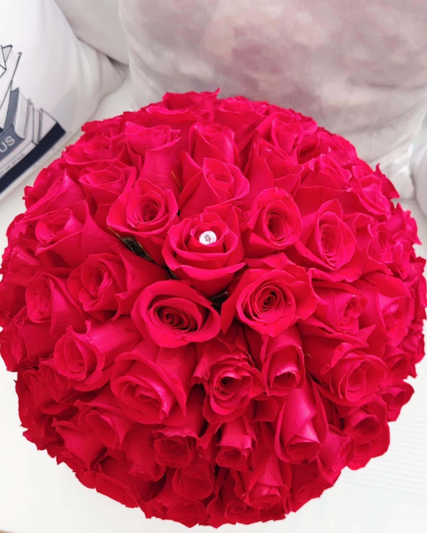 Arreglo floral con rosas grandes y frescas en una caja cilíndrica de diseño exclusivo