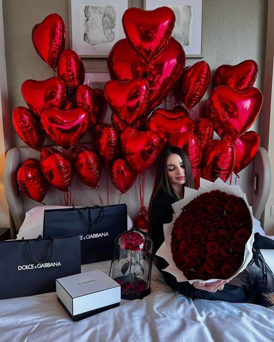 Sorpresa romántica en hotel en Madrid con globos de corazón rojos y un Burn Bouquet de rosas rojas de The Prestige Roses.