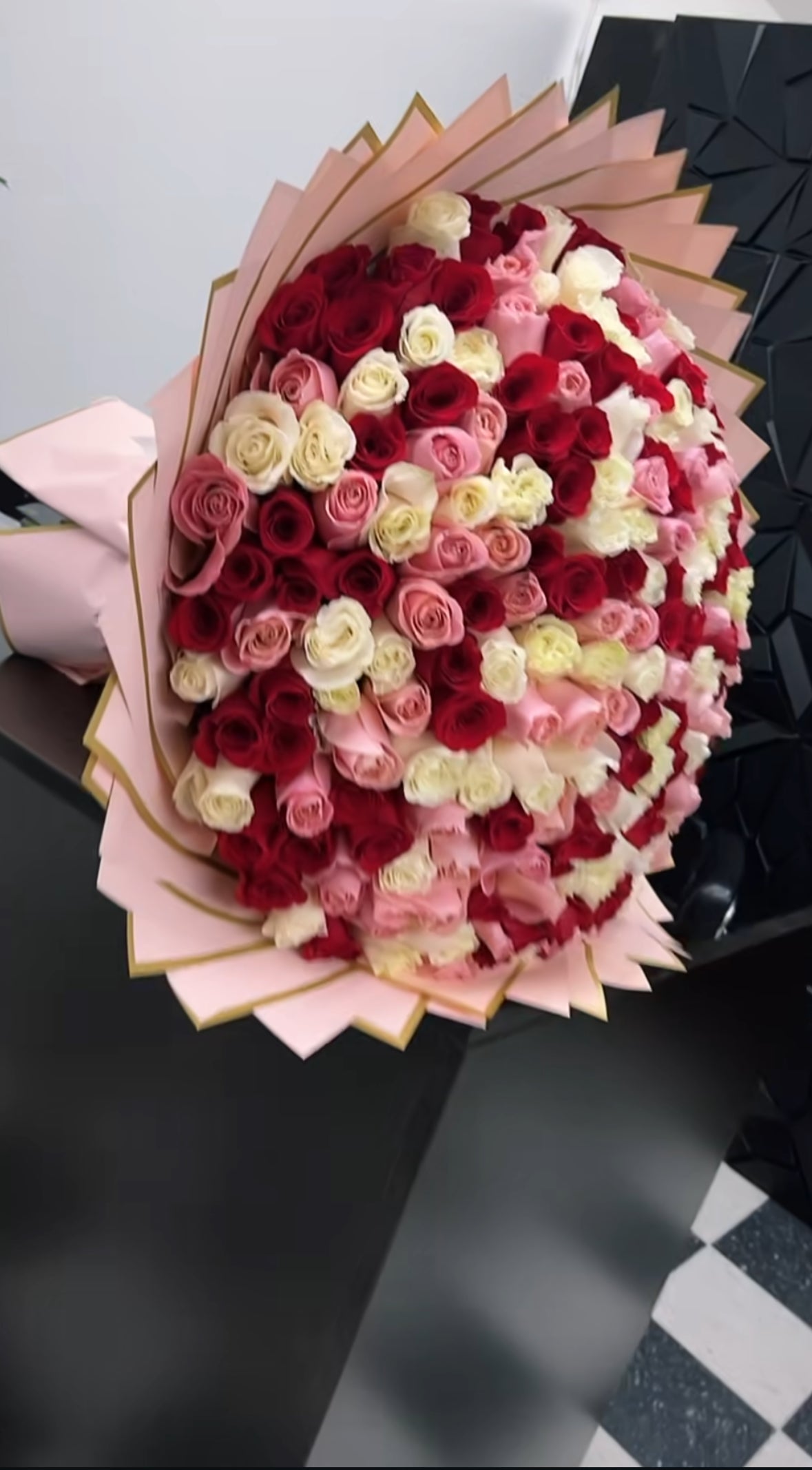 Ramo XXL de rosas rojas, rosas y blancas envuelto en papel rosa con borde dorado, diseño lujoso y elegante.
XXL bouquet of red, pink and white roses wrapped in pink paper with gold edge, luxurious and elegant design.

