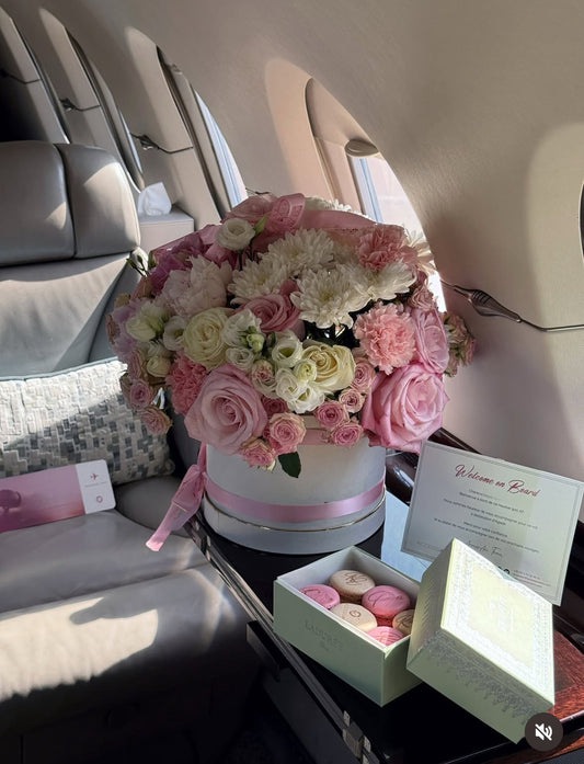 Decoración floral de lujo en jet privado con caja floral XL rosa pastel y macarons gourmet