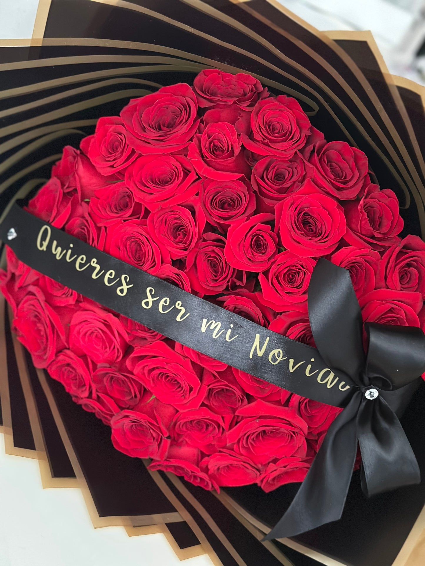 Ramo de rosas rojas frescas con cinta de satén personalizada con mensaje romántico.