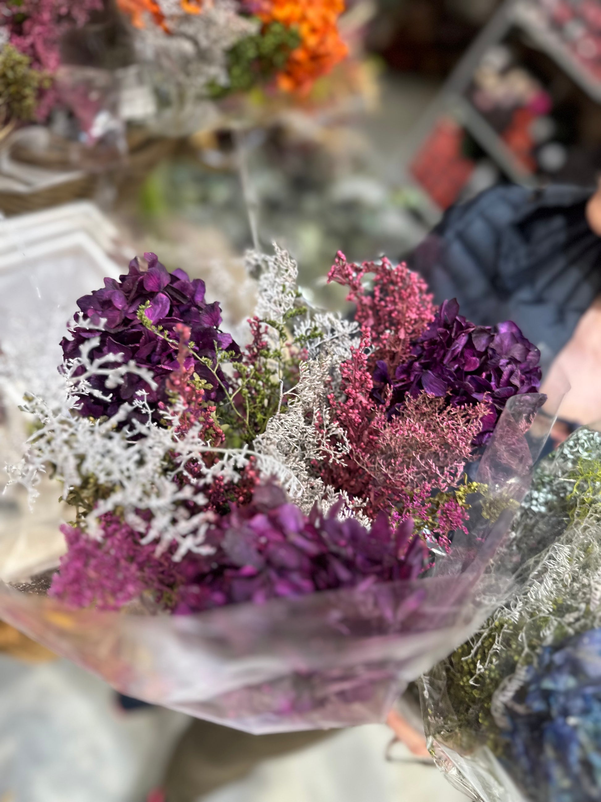 Arreglo floral seco con hortensias moradas, verdes y texturas naturales.