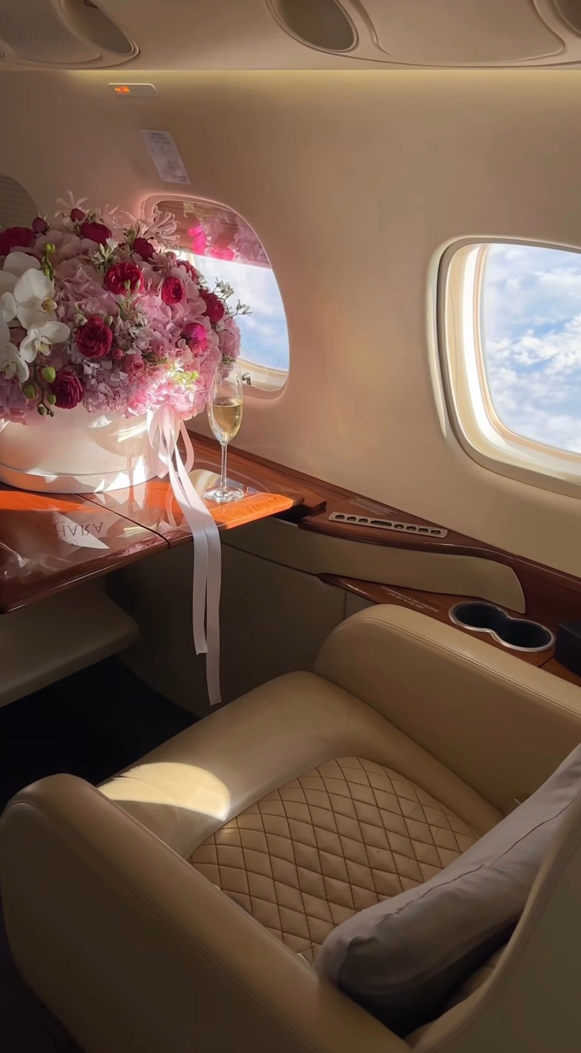 Decoración floral de lujo con rosas en tonos fucsia, blanco y burdeos en jet privado con vista al cielo.