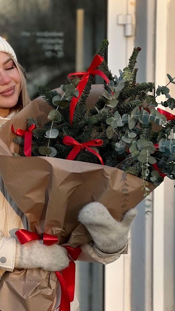 Ramo de Navidad natural con eucalipto, conos y decoración tradicional en tonos rojos y verdes.