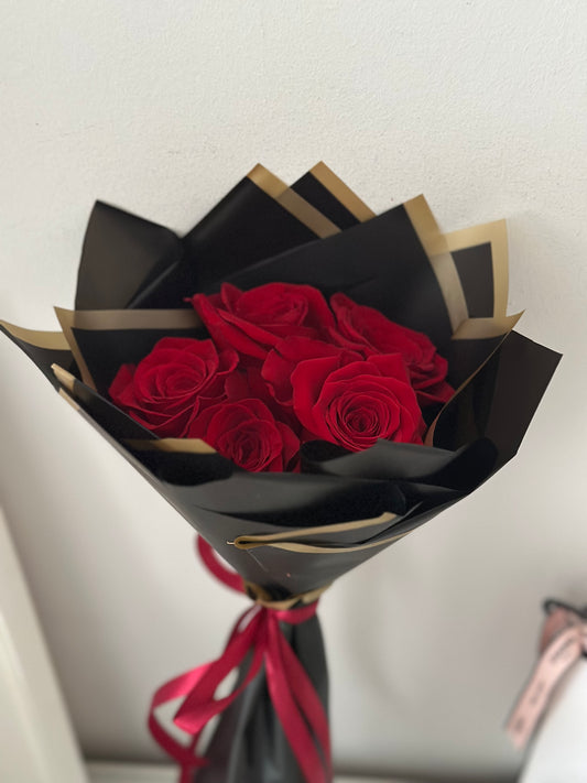 Ramo elegante de 5 rosas rojas envuelto en papel negro con borde dorado y lazo rojo en Madrid