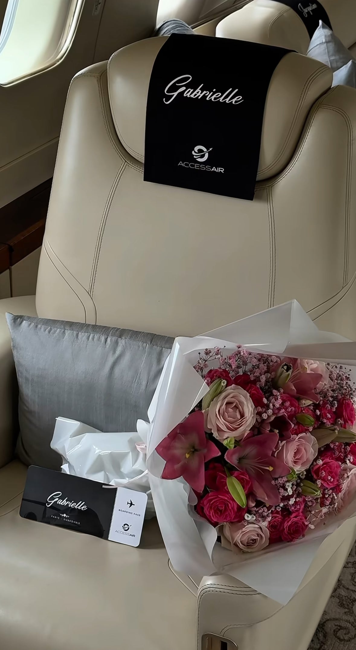 Ramo de rosas frescas en tonos fucsia y rosa sobre un asiento de jet privado con tarjeta personalizada 